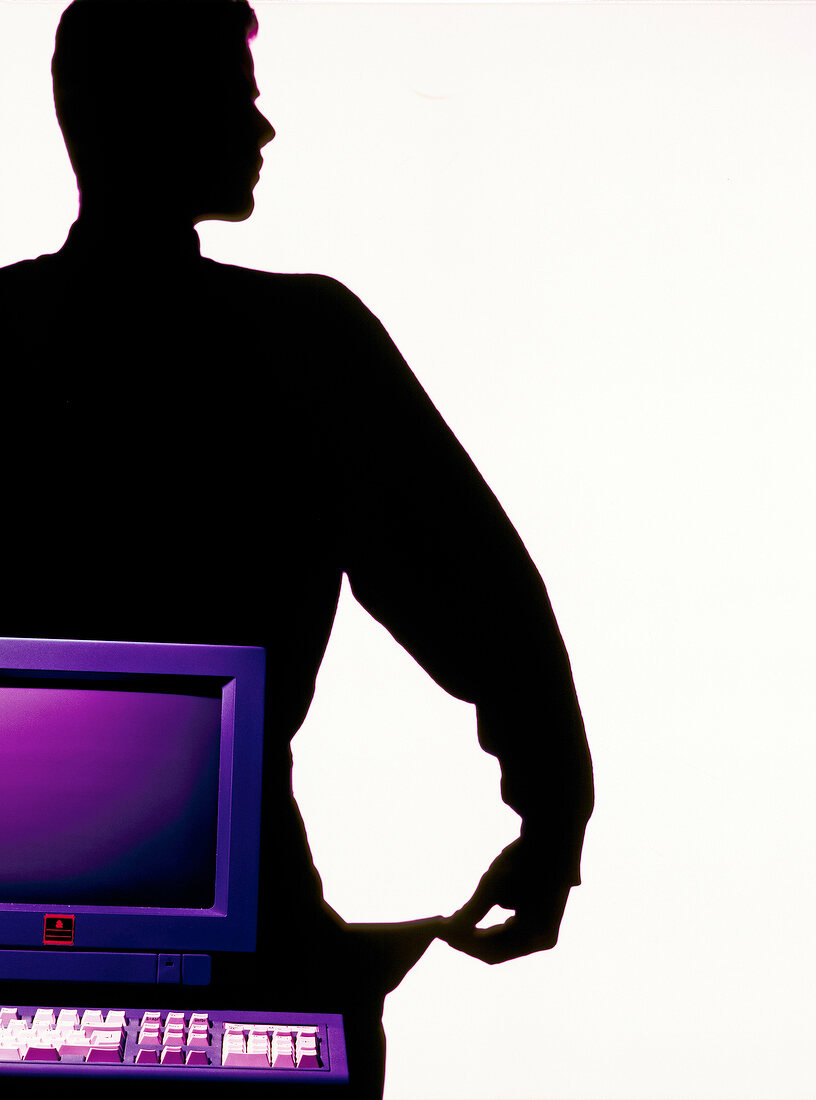 Silhouette of man pulling out his pocket standing behind a purple computer