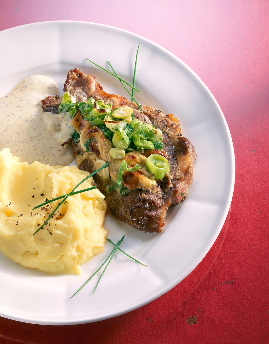 Baked neck chops with onions, mashed potatoes and mustard sauce on dish