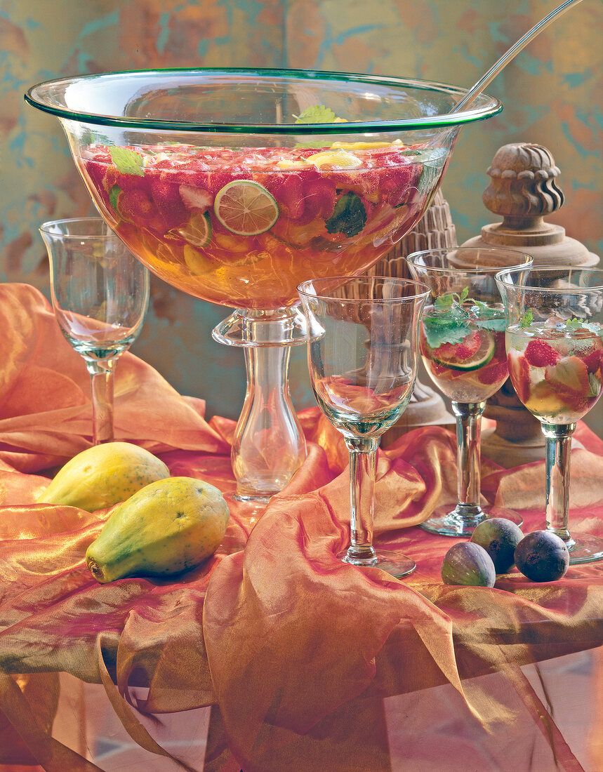 Large bowl of strawberry punch with fruits and glasses on decorated table