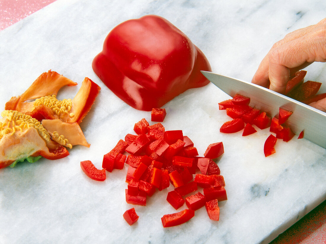 Red peppers being chopped on cutting board with knife