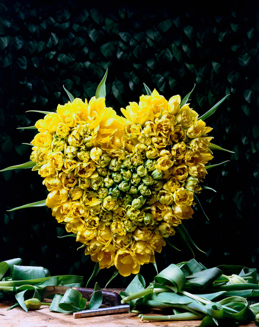 Gesteck aus gelben Tulpen in Form eines Herzens.