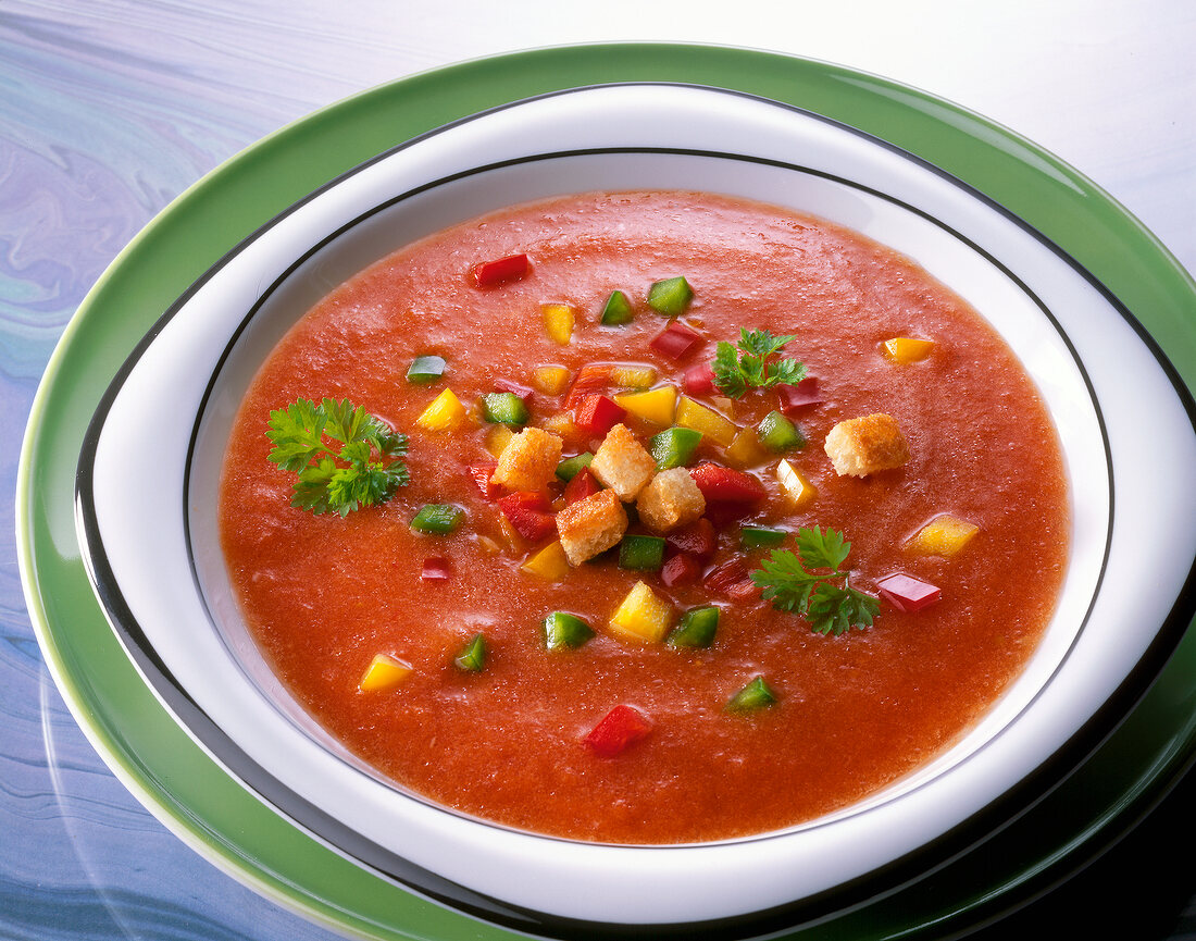 Cold soup with peppers, tomatoes, parsley and croutons in bowl