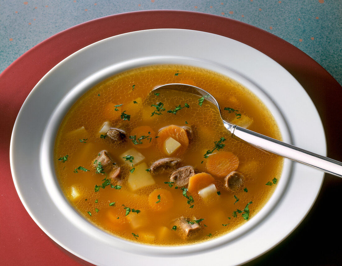 Clear oxtail soup sprinkled with parsley in bowl