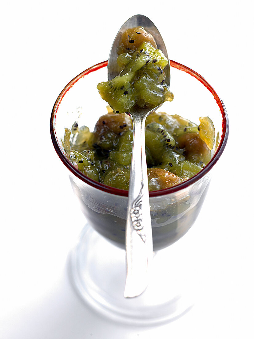Glass of gooseberry and kiwi fruit jam with spoon on it