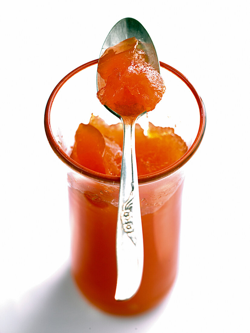 Glass of orange jelly with spoon on it