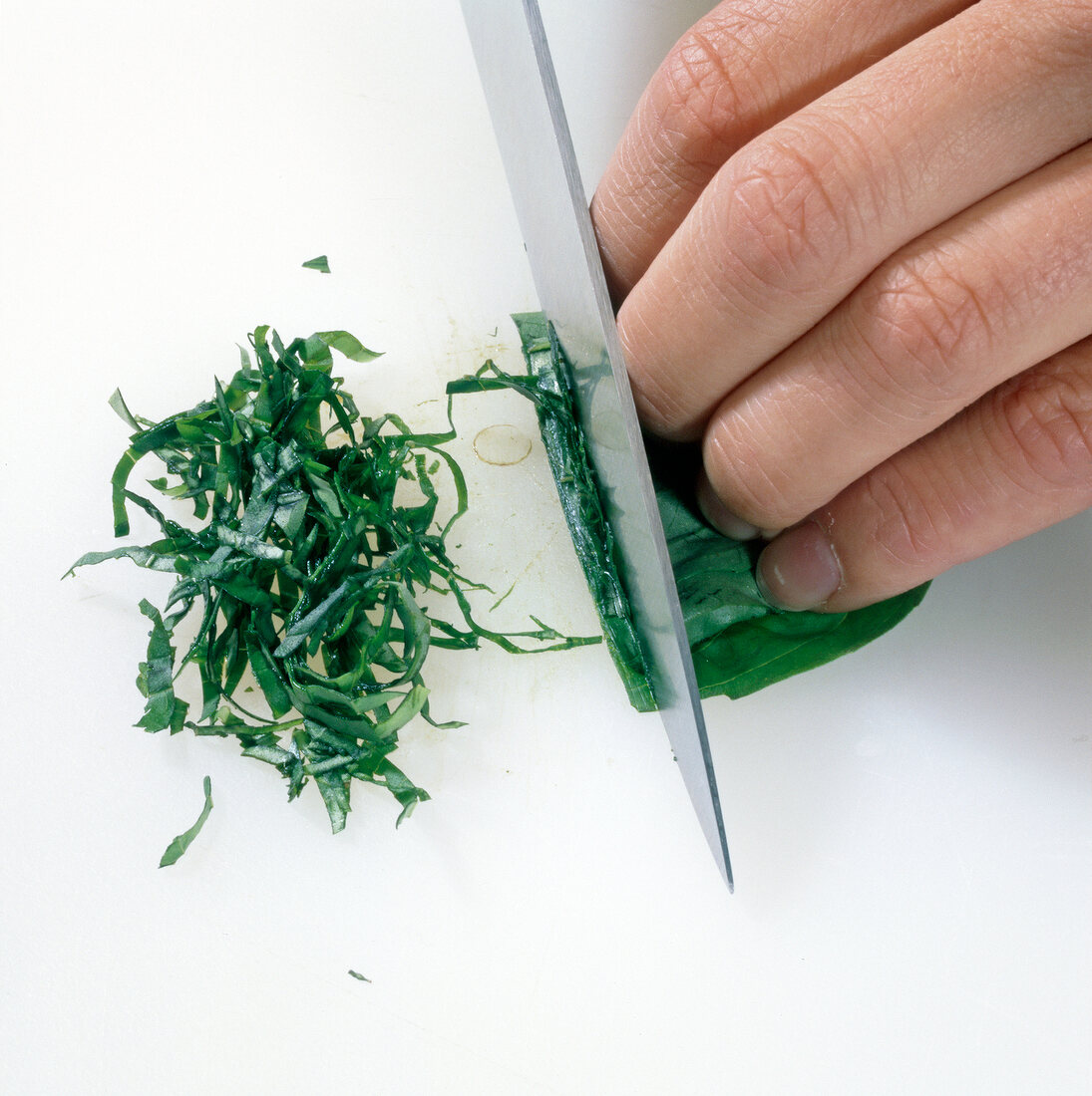 Close-up of herbs being chopped with knife