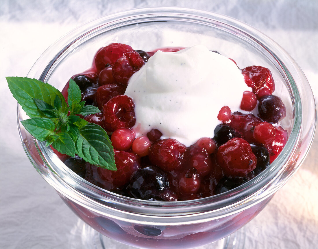 Red fruit jelly with mixed berries, topped with whipped cream and lemon balm