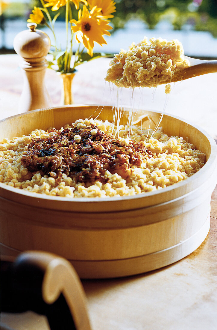 Cheese dumplings with fried onion rings in wooden pot