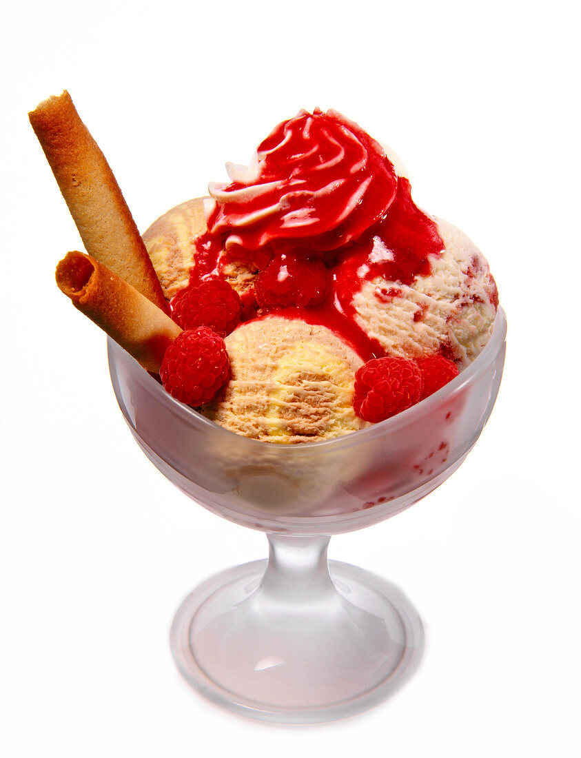 Four scoops of ice cream with raspberries, cream and wafer rolls in ice cream bowl