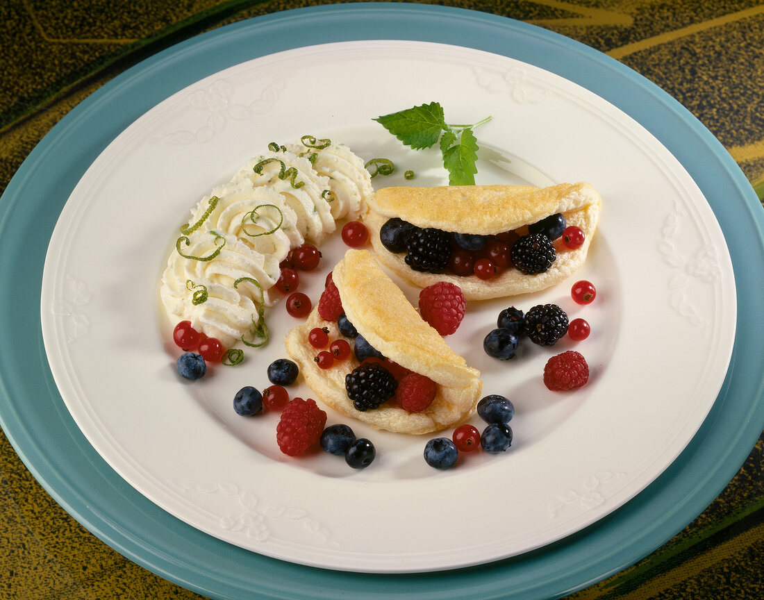 Schaumomeletts with berries, lime cream and lemon balm in dish