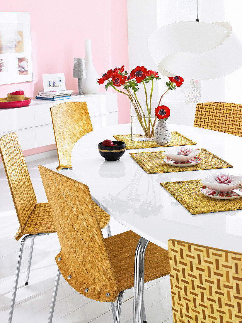Dining area with poppies in vase, bamboo chairs and white lacquer table