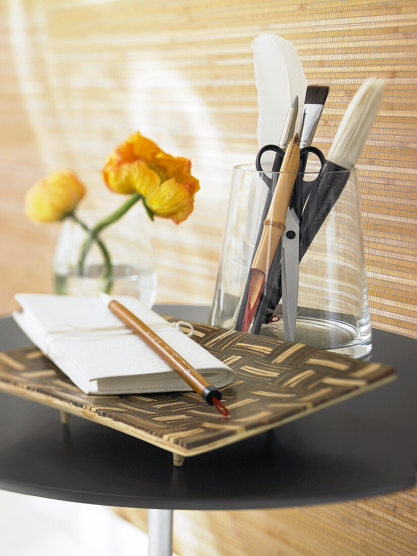 Schale aus Bambus, darauf ein Notizbuch u. Stift, Schreibwaren im Glas