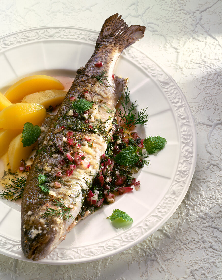 Close-up of herb trout with onions served with boiled potatoes