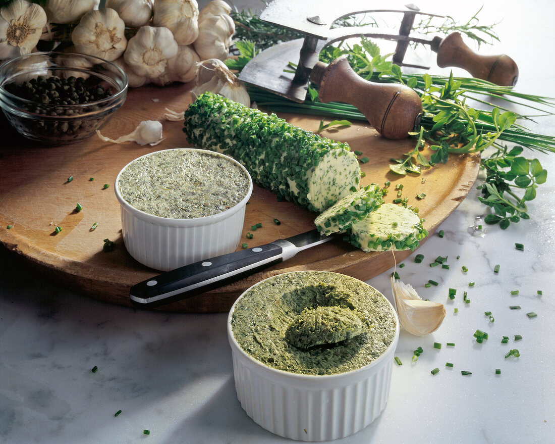 Various herb butter blends in bowls with ingredients on wooden board