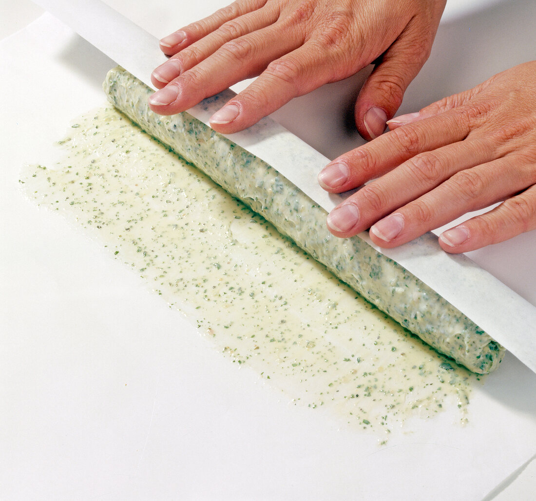 Whisked batter being spread on baking paper and rolled while preparing herb butter, step 6
