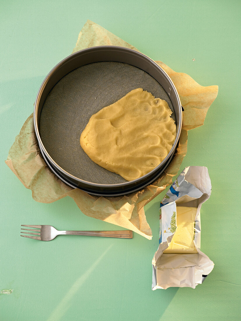 Short crust pastry being pressed into a spring form pan with baking paper in it