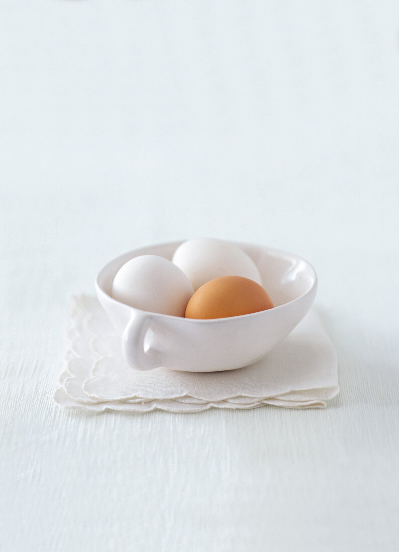 Tasse mit zwei weißen und einem braunen Ei