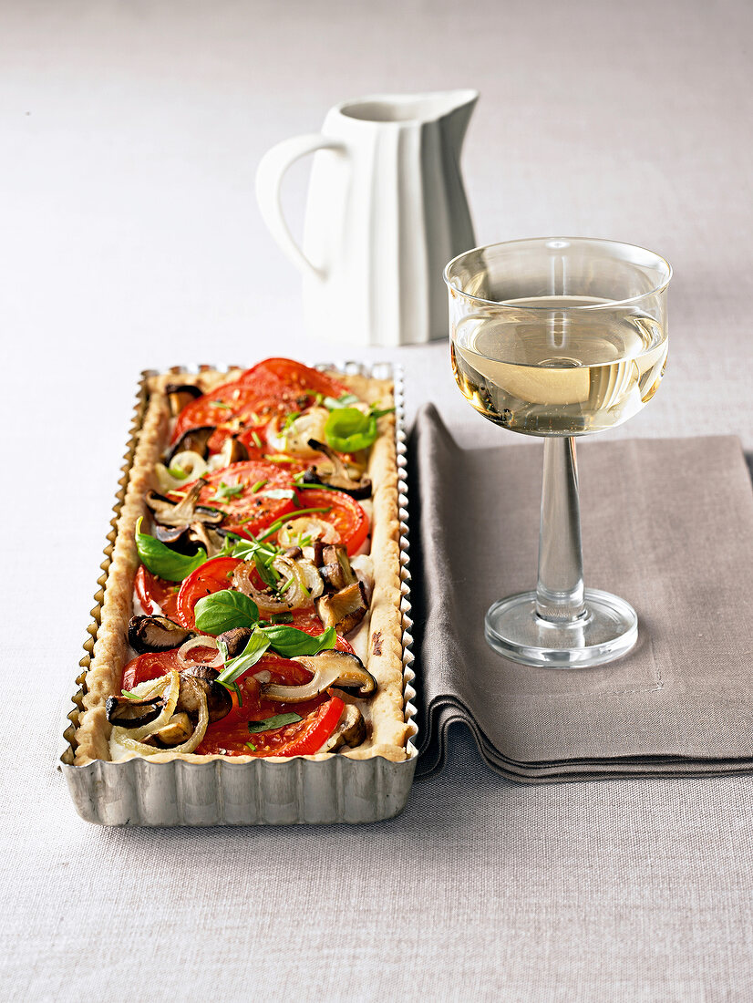 Close-up of tomato and herb tart with ricotta and glass of champagne