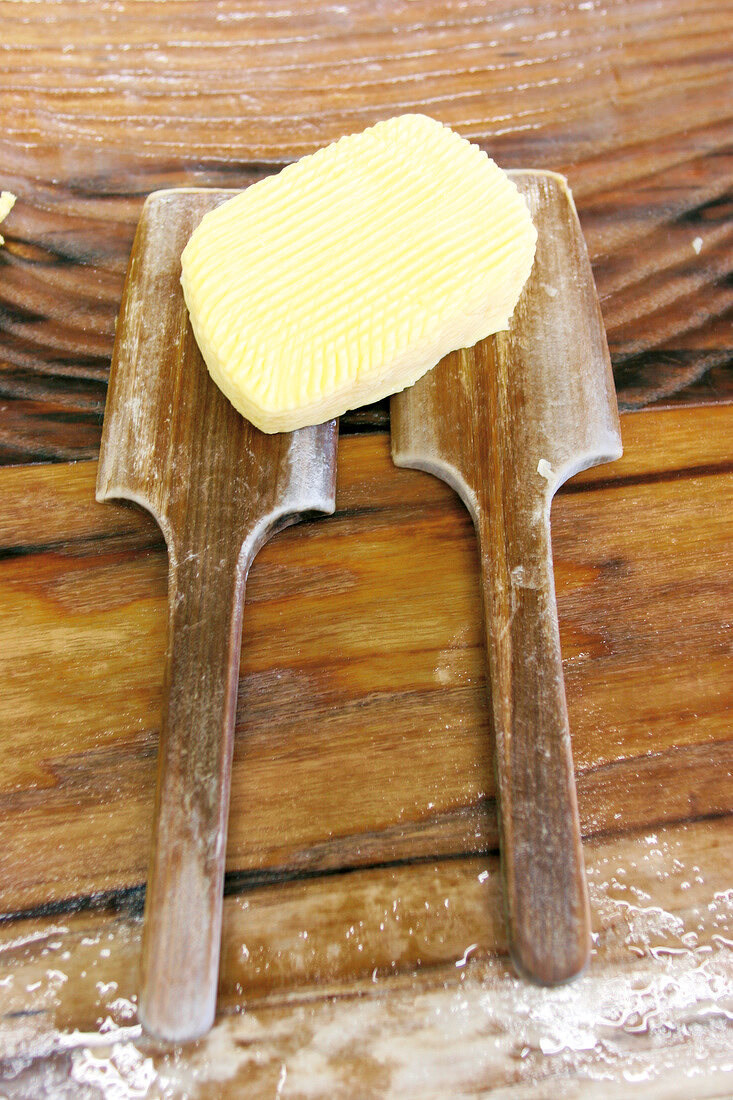 Ein Stück Butter liegt auf zwei Holz-Spateln