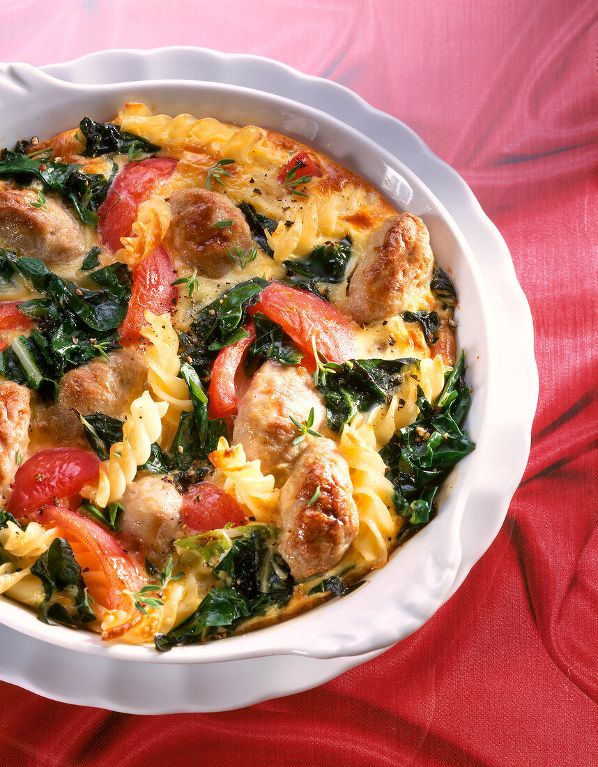 Close-up of pasta bake with Swiss chard, tomatoes and sausage in bowl