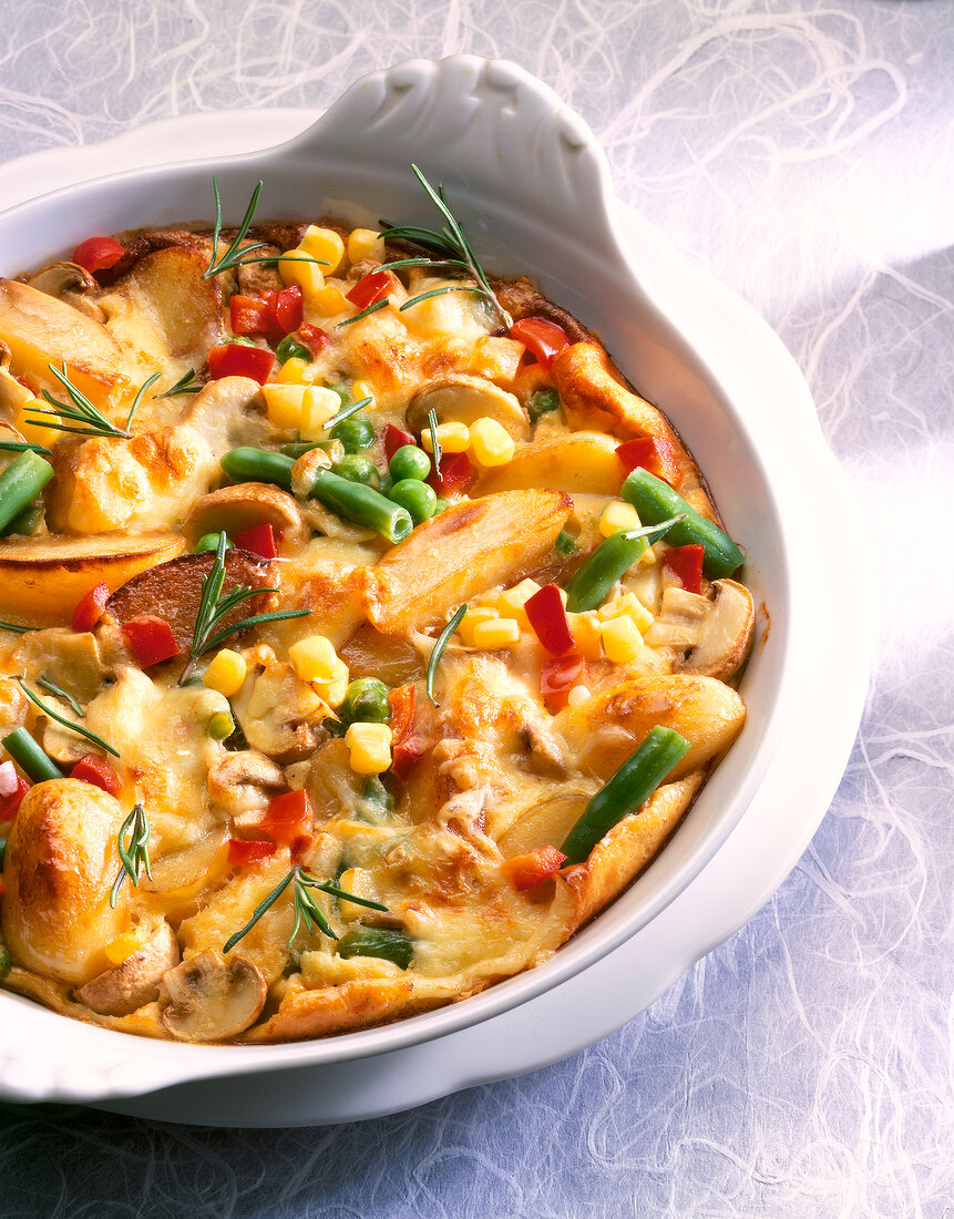 Close-up of potato and vegetable casserole with corn, peas, beans, mushrooms and rosemary