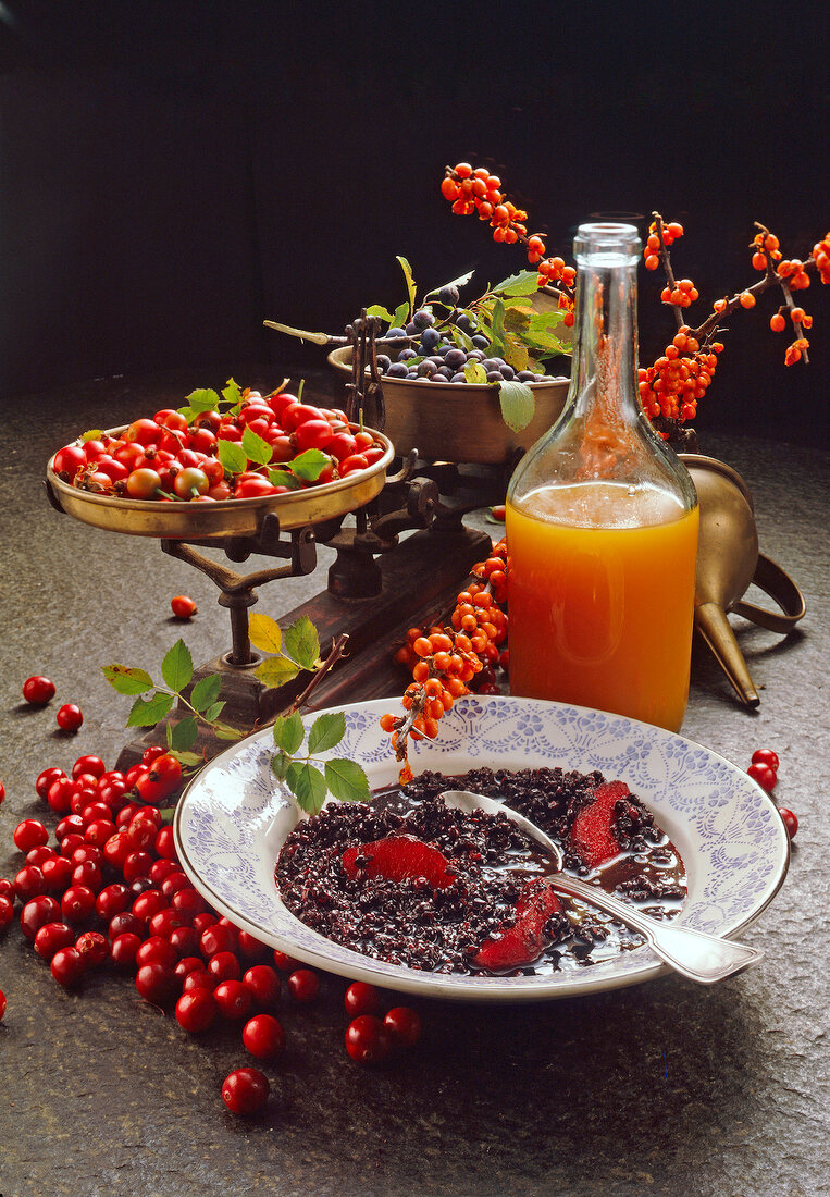 Sea buckthorn and blackthorn in weighing machine beside carafe with juice