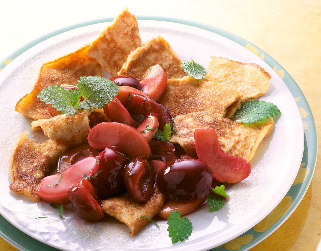 Close-up of almond pancakes with plums on plate