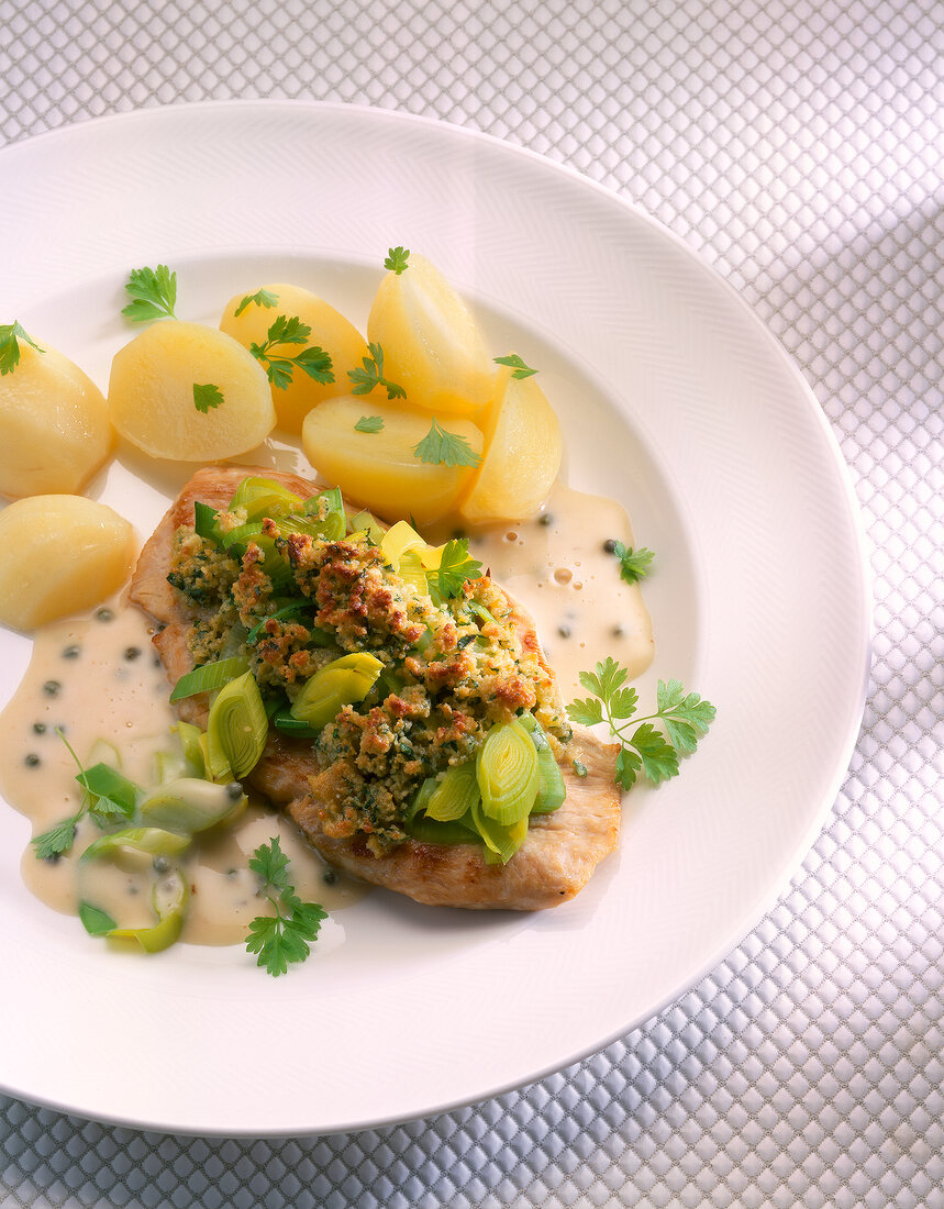 Close-up of baked turkey schnitzel with potatoes and leeks in dish
