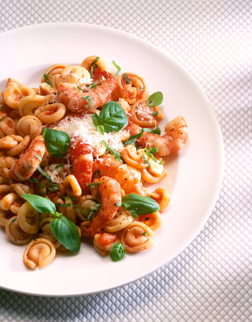 Pasta with shrimp, tomatoes, basil and parmesan cheese on plate