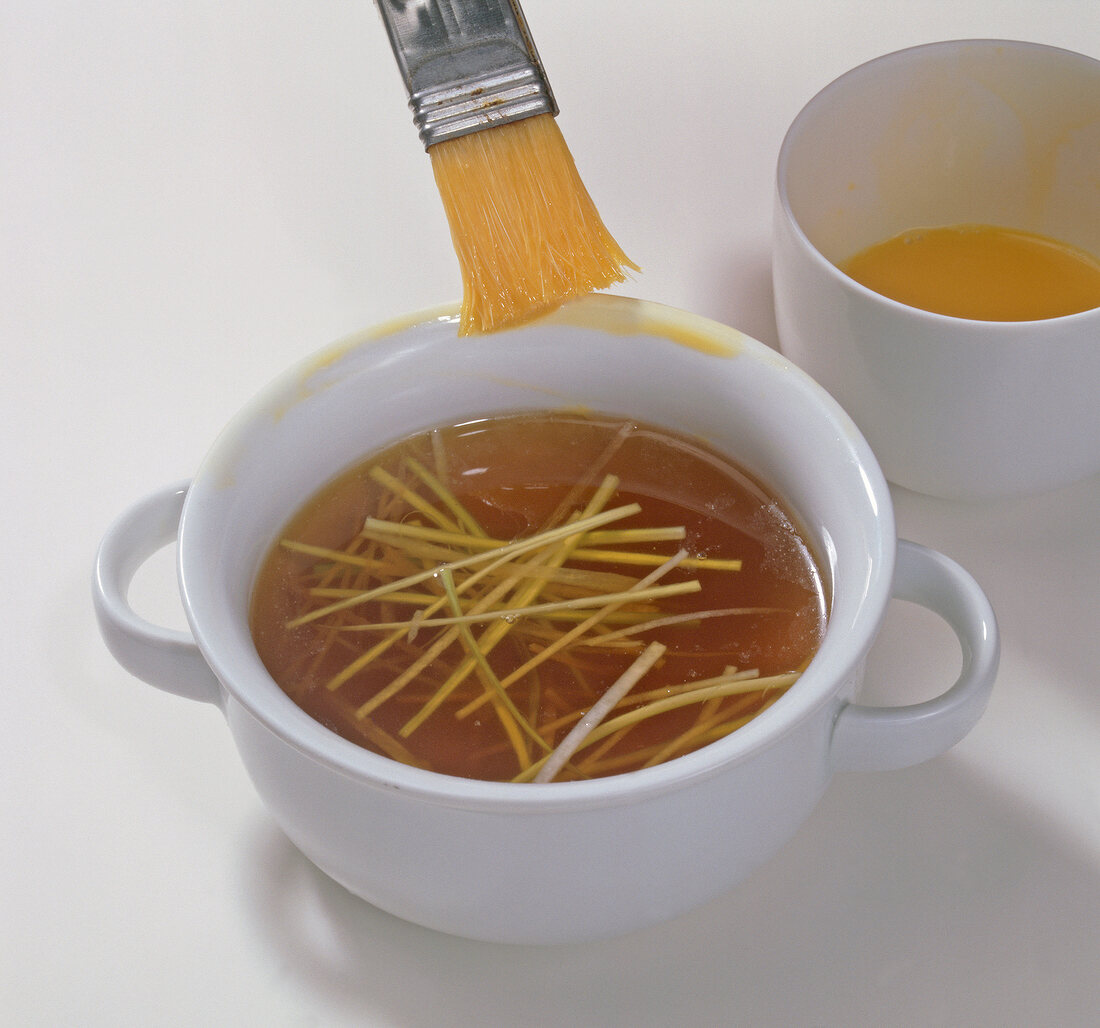 Applying egg yolk on edge of cup with brush, step 1