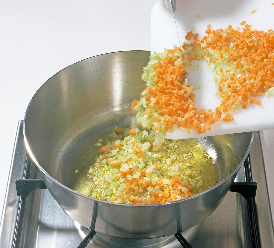 Shallots and garlic being added in oil in pan, step 1