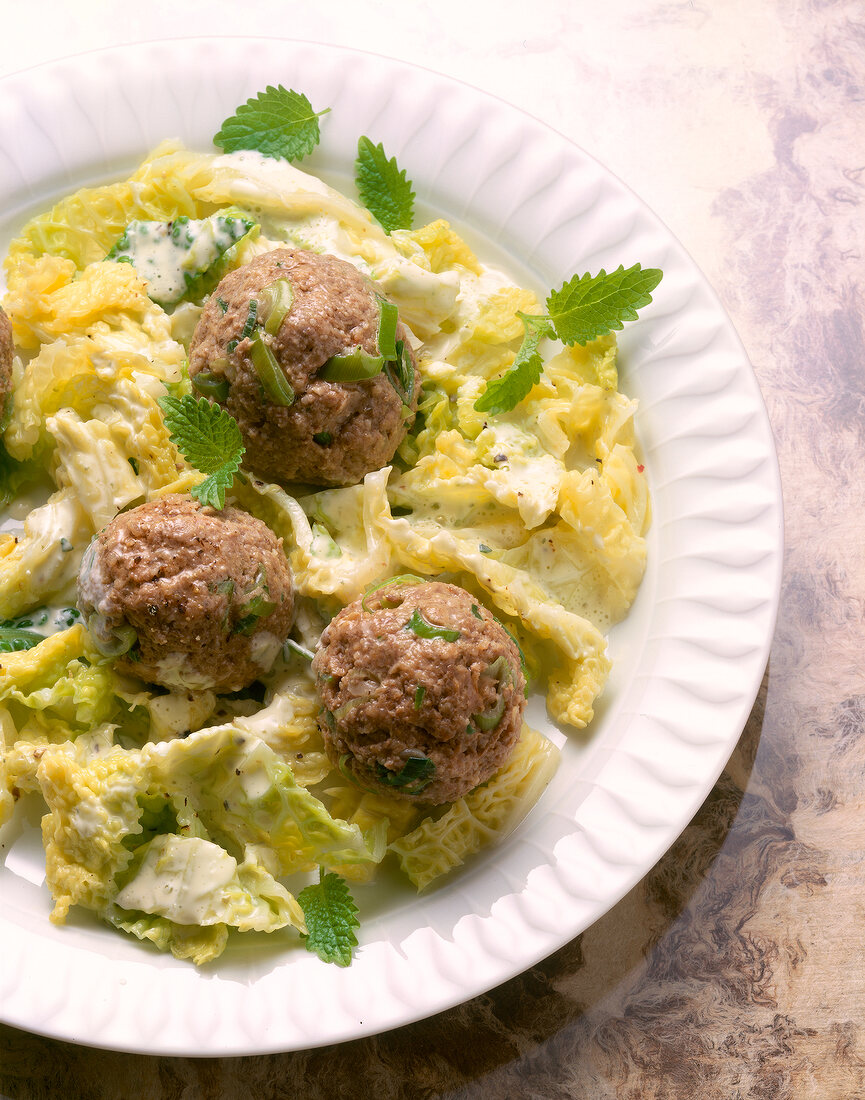 Close-up of savoy cabbage with meatballs and mint leaves on plate