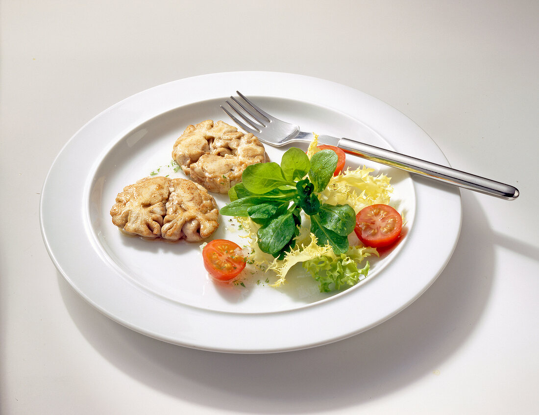 Slices of fried deer brain with salad on plate