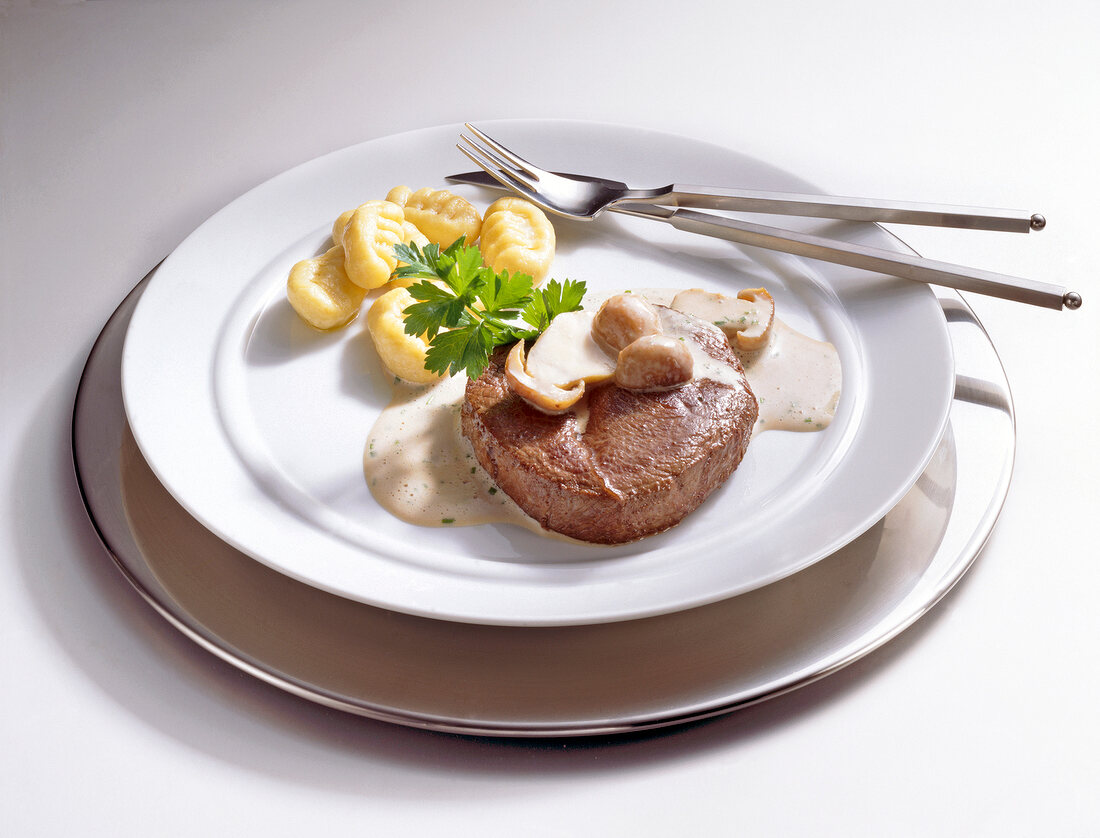 Venison steak with mushroom sauce and gnocchi on plate