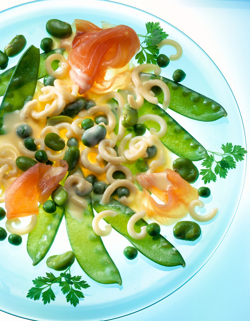 Close-up of vegetable salad with salmon, pasta, broad beans and peas