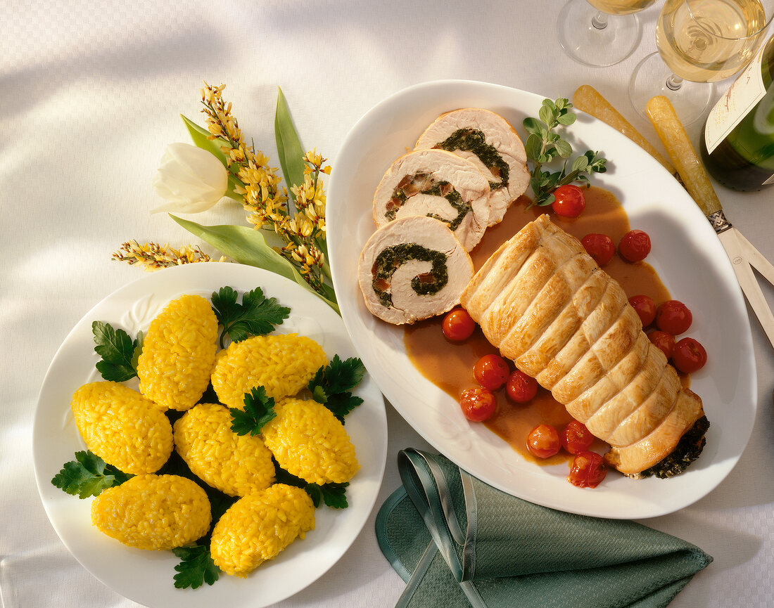Roasted turkey roll stuffed with spinach and saffron risotto on parsley leaves on plate