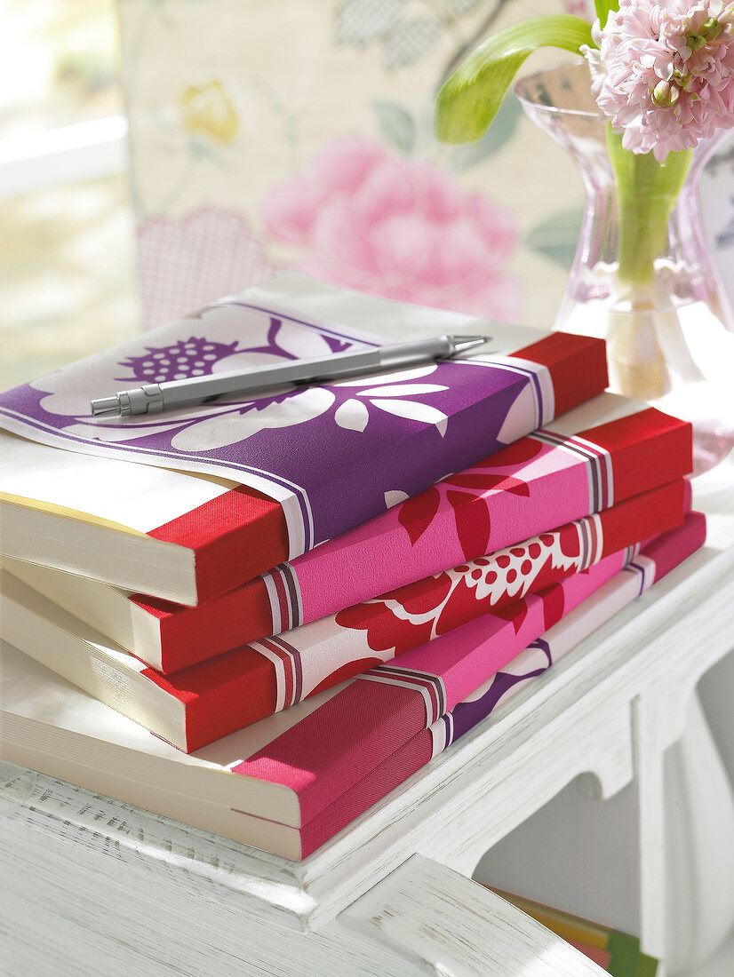 Stack of book wrapped with colourful floral cover on table