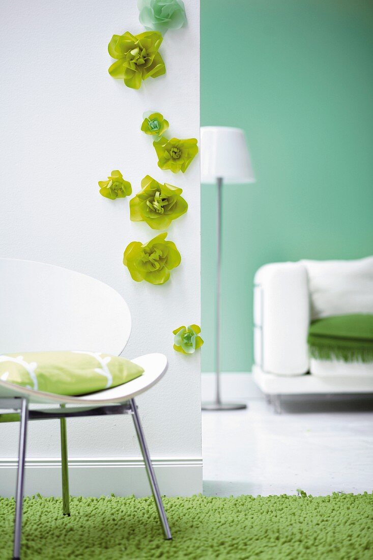 White wall with green flowers and cushion on chair