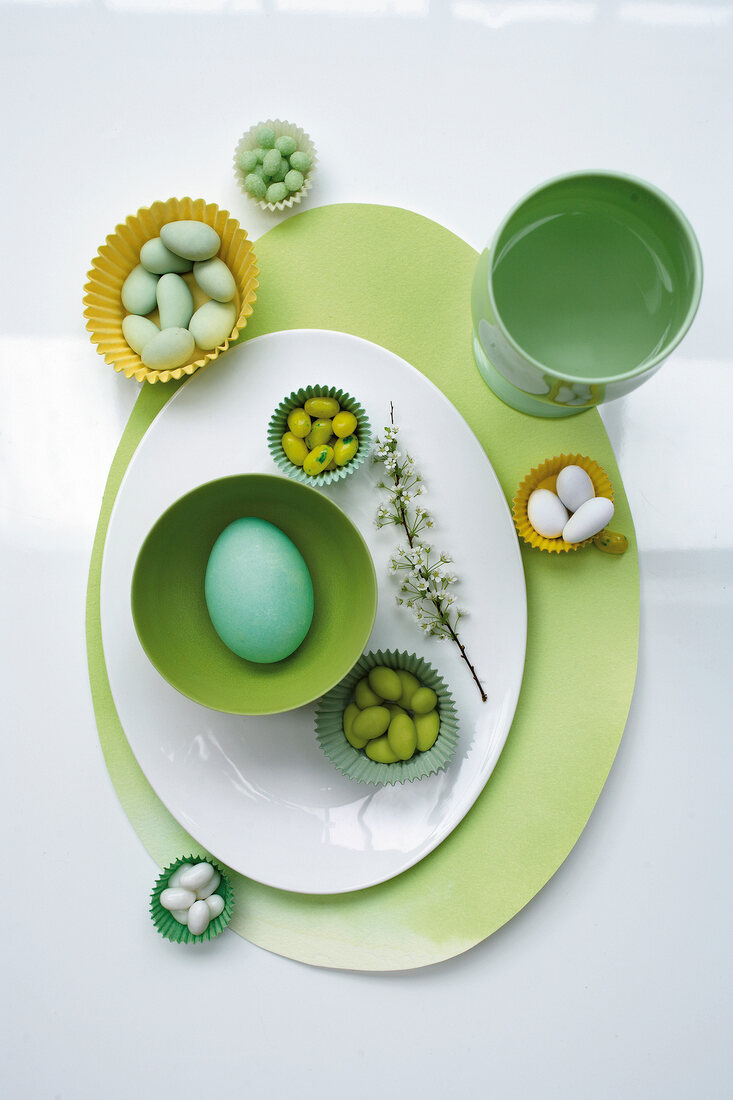Easter eggs and candies in paper cases with oval white and green plate