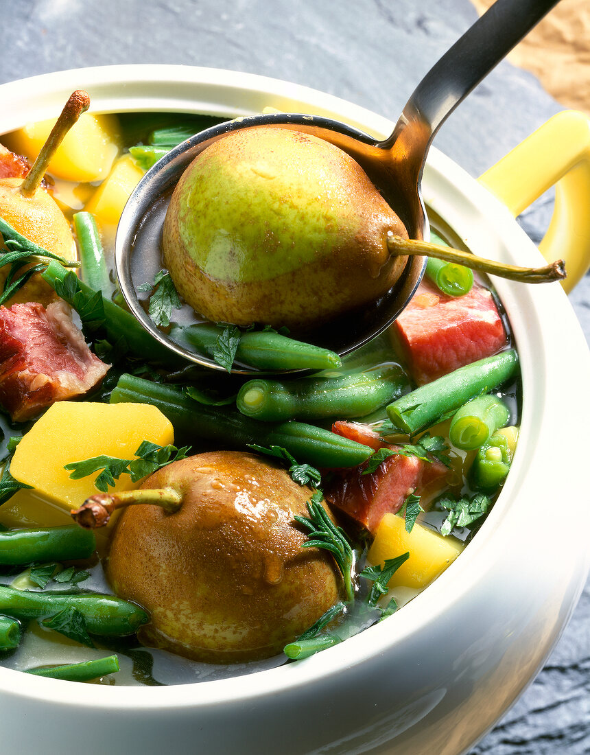 Close-up of stew with pears, beans and bacons in soup pan