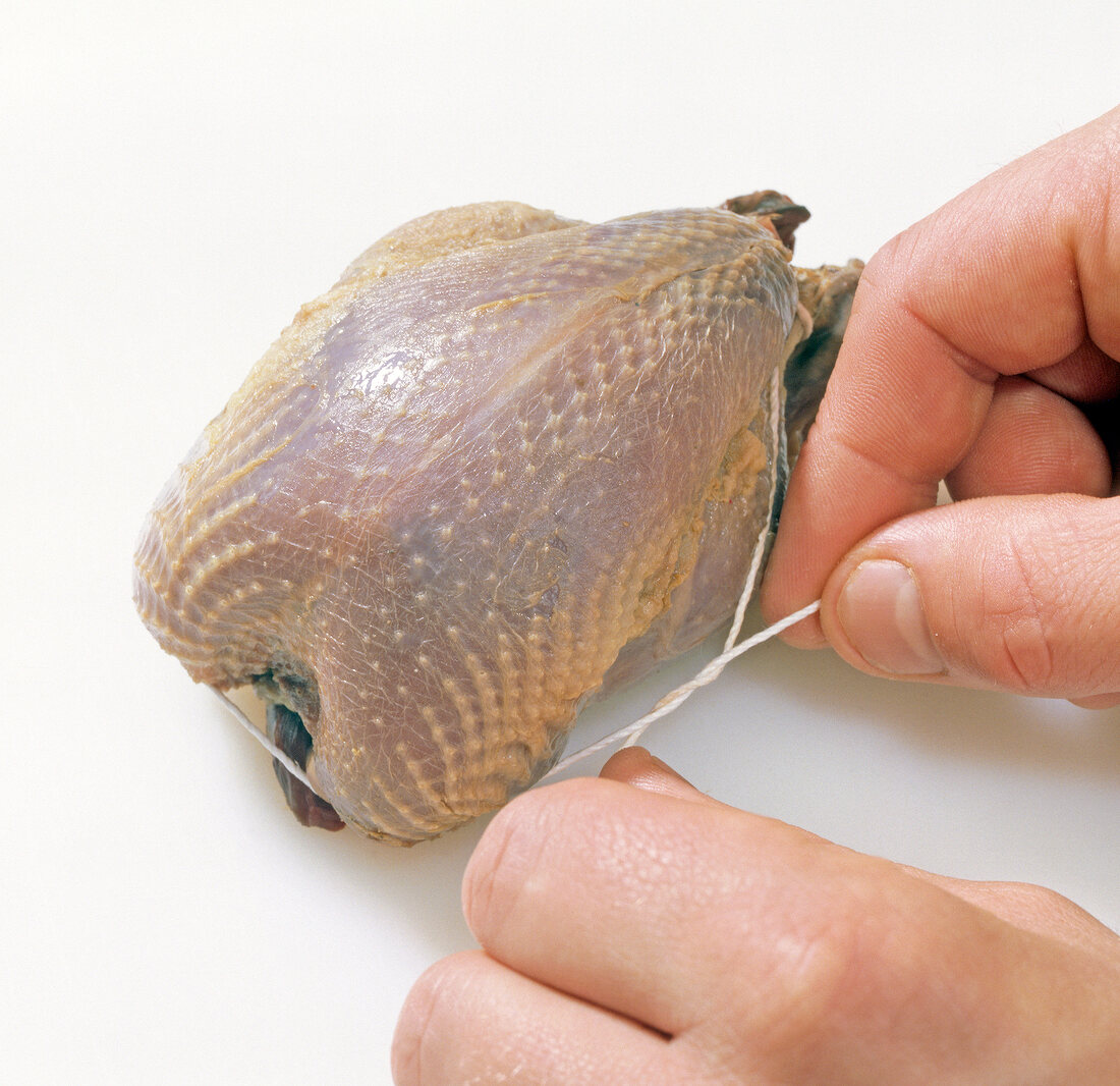 Partridge being tied with kitchen string, step 1