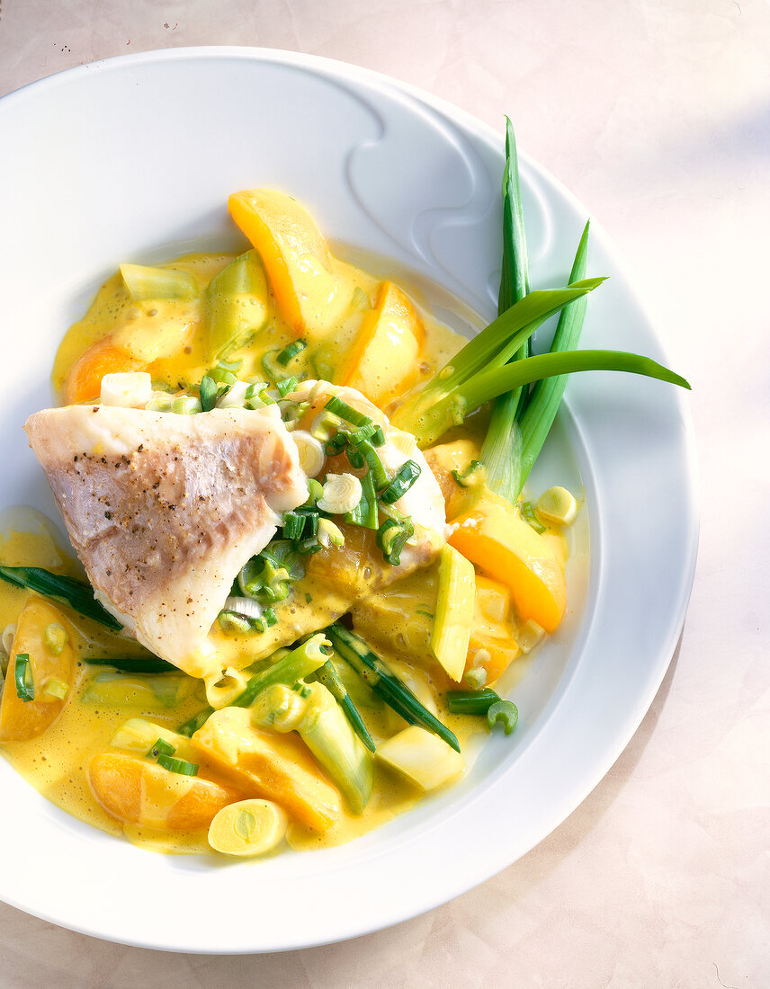 Close-up of redfish fillet with apricots, green onions and curry on plate