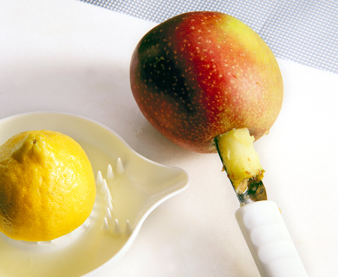 Close-up of apple core being removed from apple corer, citrus squeezer with lemon on side