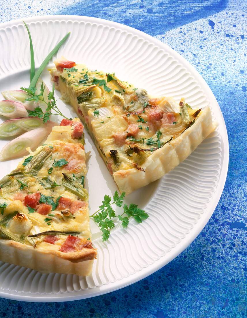 Close-up of spring onion quiche with parsley on plate