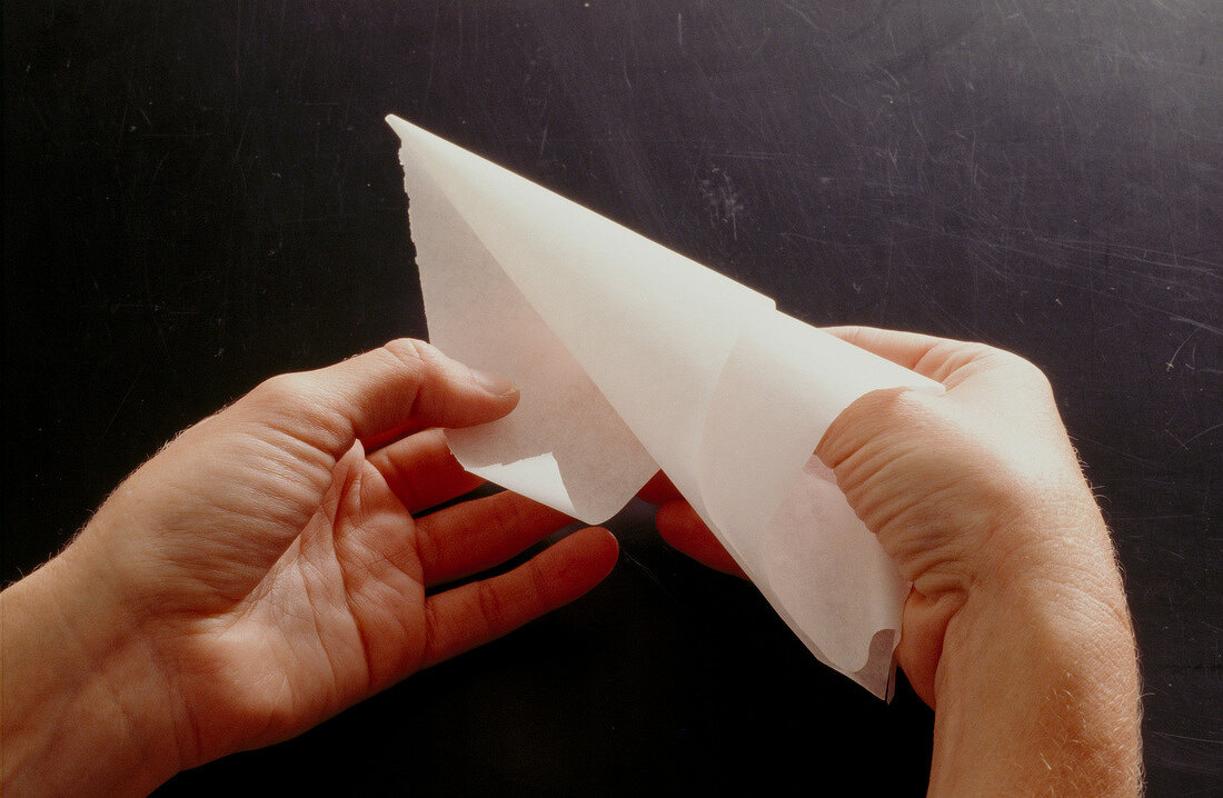 Triangular baking paper being rolled into a bag, step 3