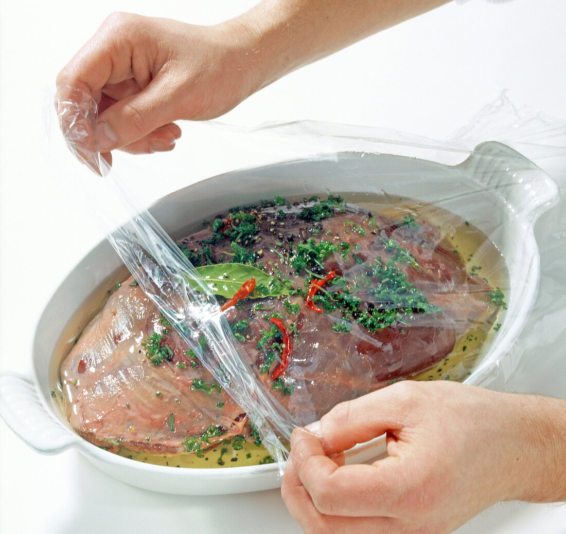 Covering casserole of mouflon meat with foil while preparing mufflonkeule, step 2