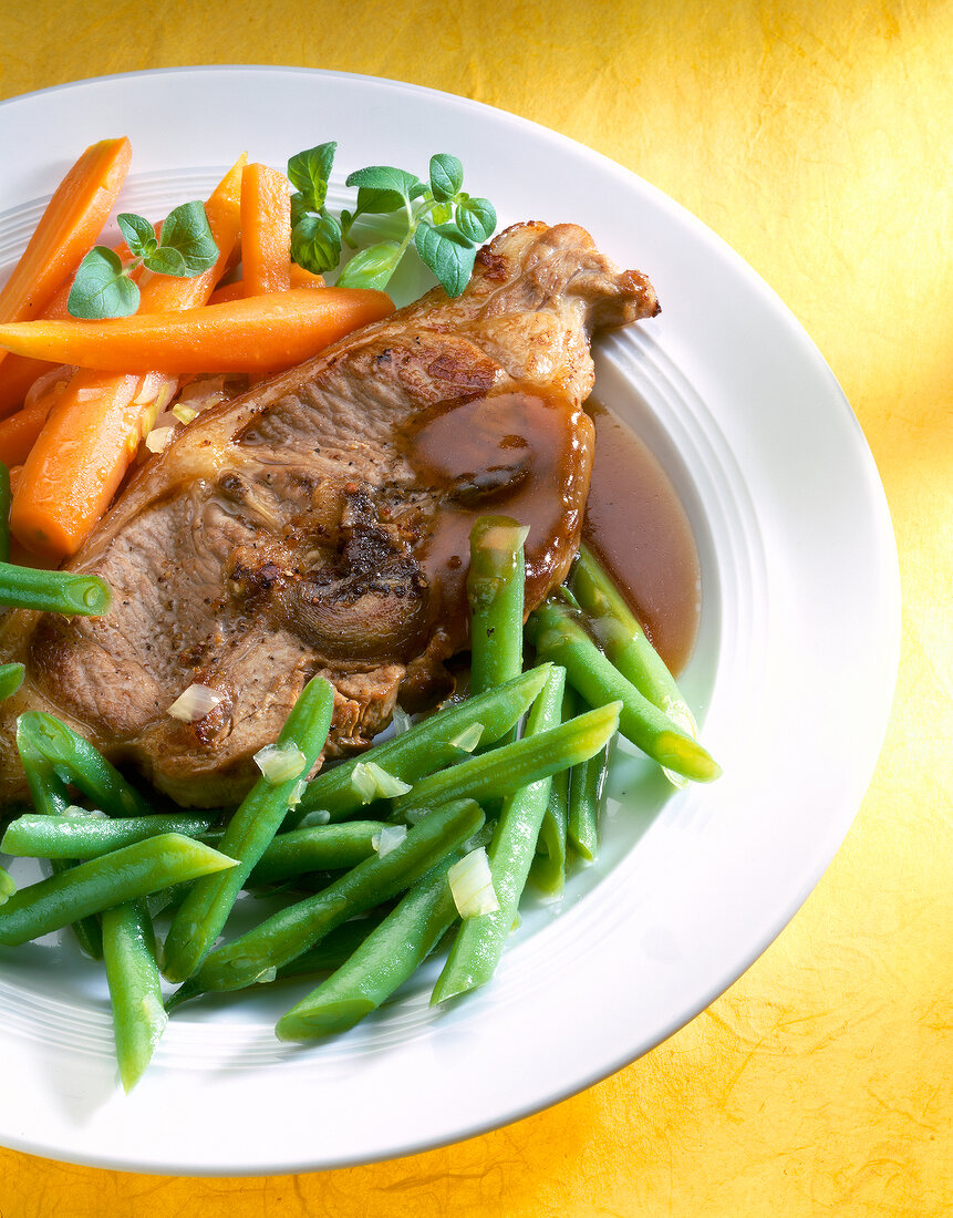 Close-up of lamb chops with vegetables and sauce on plate