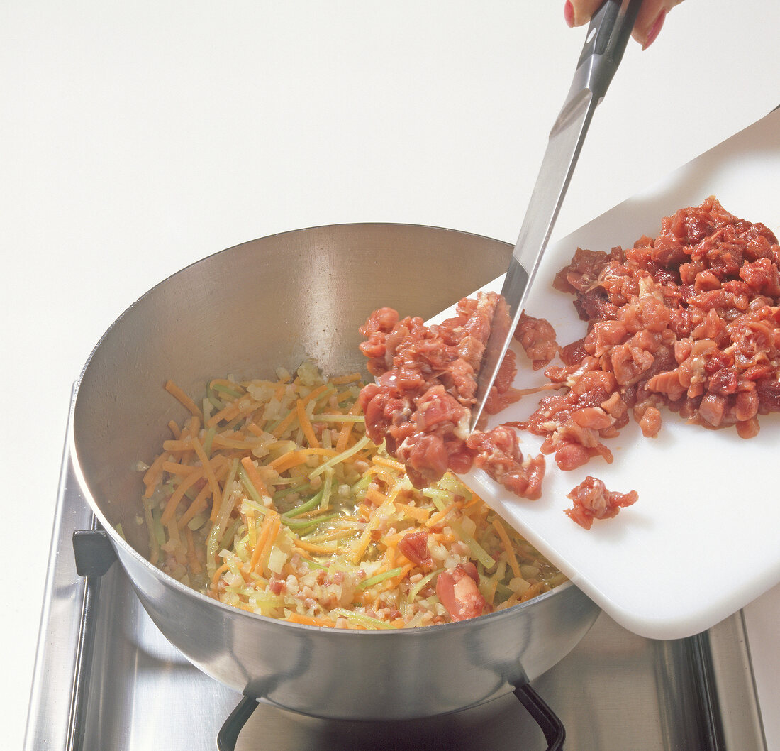 Meat being added to vegetables while preparing wild duck ragout, step 3