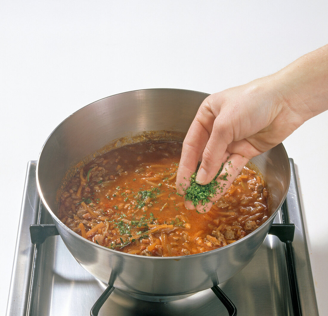 Sprinkling parsley on vegetables and meat while preparing wild duck ragout, step 6