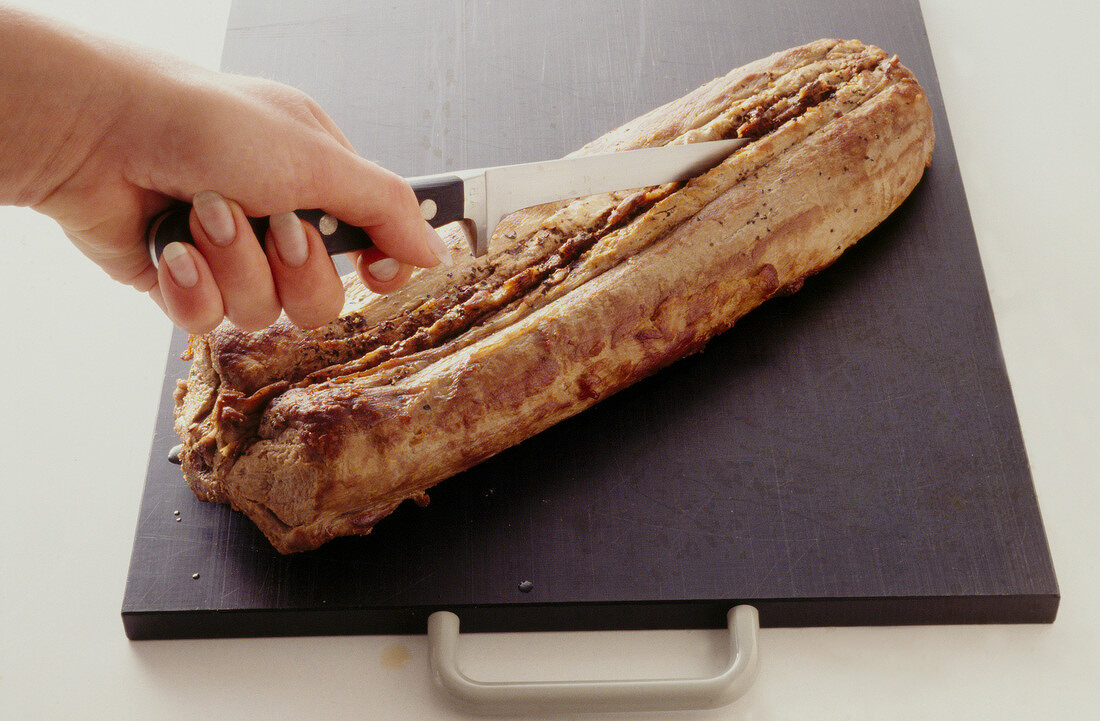 Venison being cut with knife on wooden board